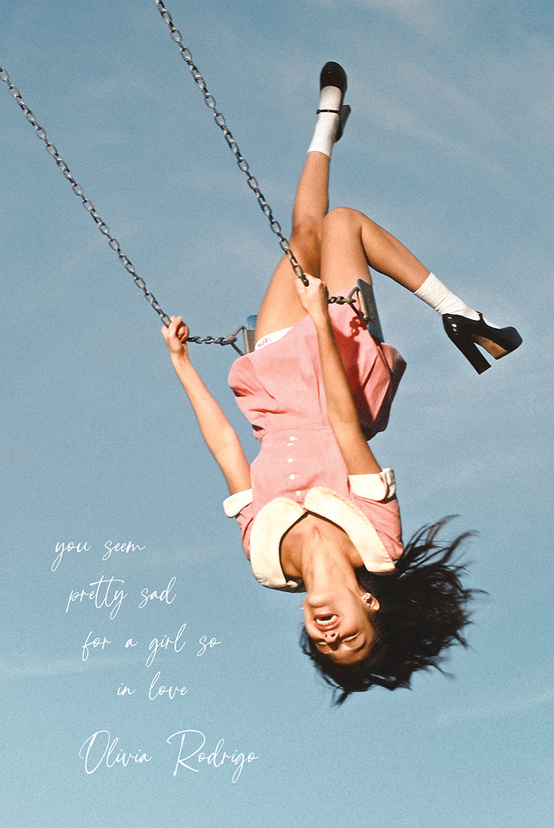 Olivia Rodrigo poster featuring Olivia Rodrigo hanging upside down on a swing against a pale blue sky